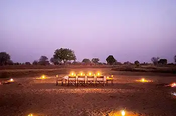 Dine along the Luangwa River as the sun begins to set